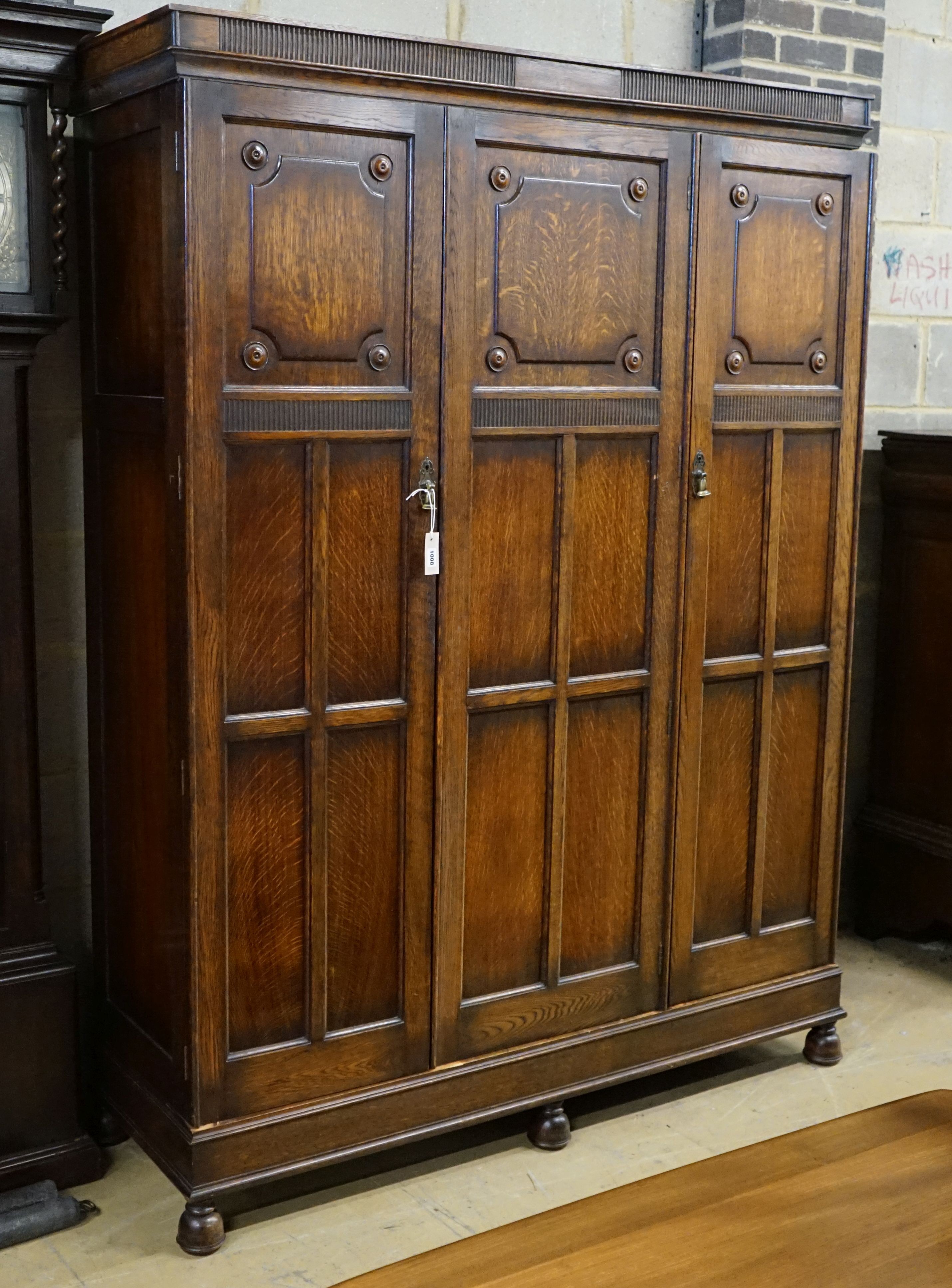 A carved and panelled oak triple wardrobe with fitted interior, length 150cm, depth 49cm, height 200cm